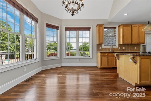 kitchen featuring dark wood-type flooring, a notable chandelier, backsplash, and baseboards