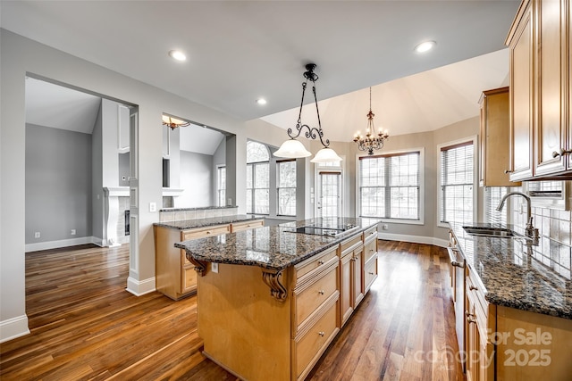 kitchen featuring vaulted ceiling, a sink, black electric cooktop, and a center island