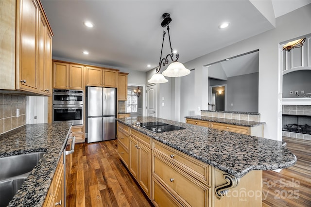 kitchen featuring decorative backsplash, a tile fireplace, dark wood-style floors, a center island, and stainless steel appliances