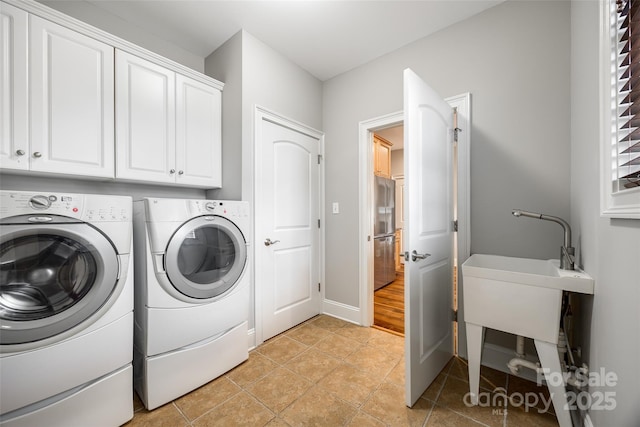 laundry room with light tile patterned floors, washing machine and dryer, cabinet space, and baseboards