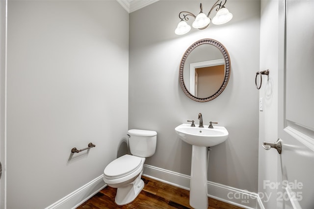 half bath featuring toilet, a sink, baseboards, and wood finished floors