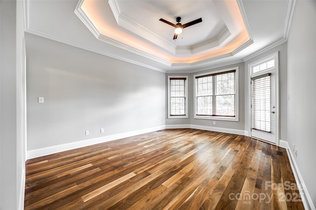 unfurnished room with dark wood-style floors, a tray ceiling, a ceiling fan, and baseboards