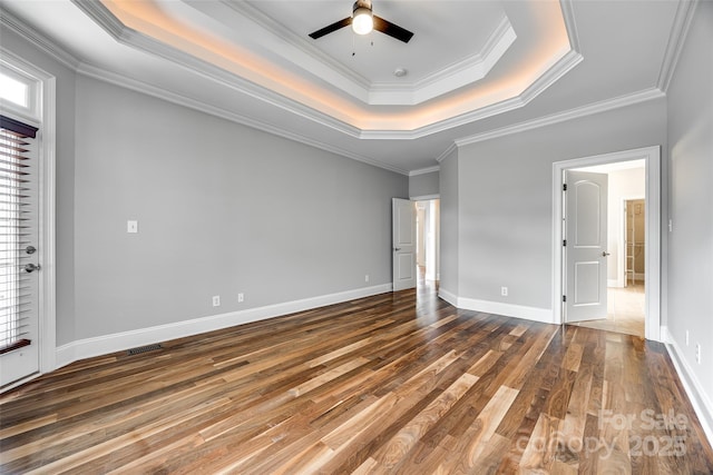 unfurnished bedroom featuring visible vents, baseboards, ornamental molding, hardwood / wood-style floors, and a raised ceiling