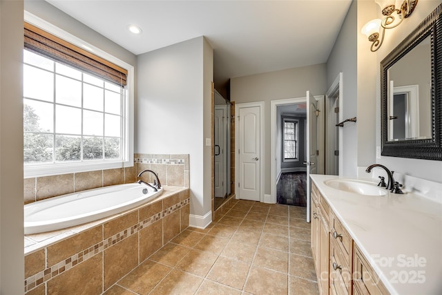 full bathroom with a wealth of natural light, a garden tub, vanity, and tile patterned floors