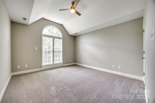 carpeted spare room featuring baseboards, vaulted ceiling, and a ceiling fan