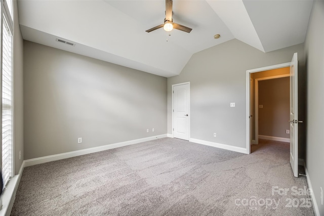 unfurnished bedroom with carpet floors, visible vents, baseboards, vaulted ceiling, and multiple windows