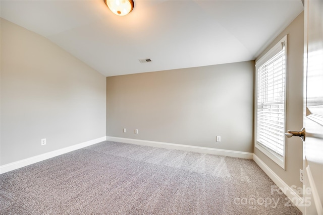 carpeted empty room with baseboards, visible vents, and vaulted ceiling