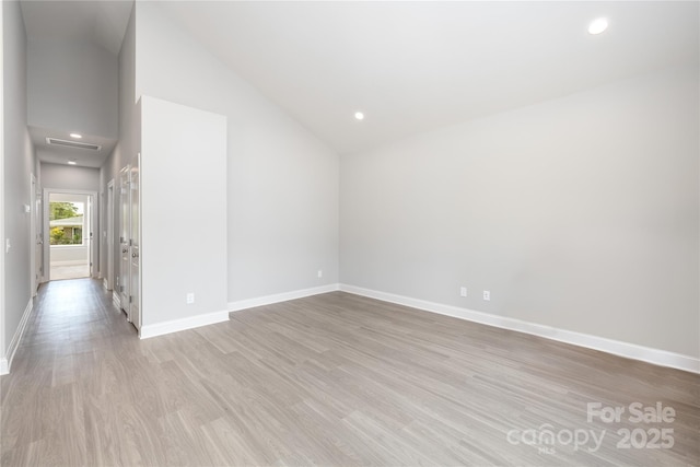 spare room with light hardwood / wood-style flooring and vaulted ceiling