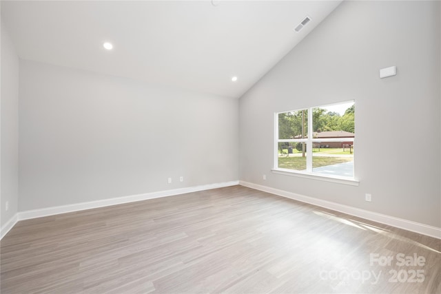 empty room featuring high vaulted ceiling and light wood-type flooring