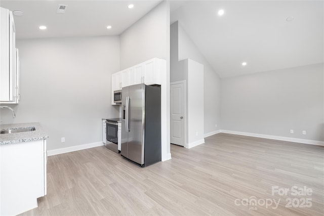 kitchen with sink, light stone counters, white cabinetry, light hardwood / wood-style flooring, and stainless steel appliances