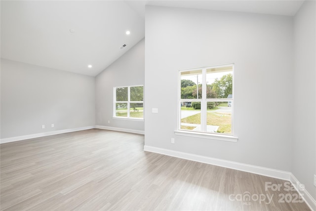 empty room featuring high vaulted ceiling and light hardwood / wood-style flooring