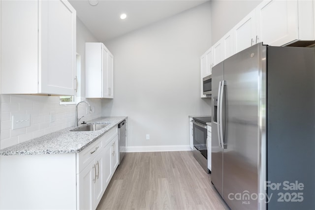 kitchen with sink, appliances with stainless steel finishes, white cabinetry, light stone counters, and decorative backsplash