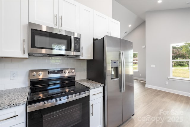 kitchen with white cabinetry, light stone countertops, decorative backsplash, and stainless steel appliances