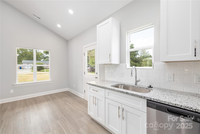 kitchen with lofted ceiling, sink, white cabinetry, dishwasher, and light stone countertops