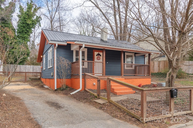 bungalow-style home featuring a fenced front yard, a chimney, metal roof, a gate, and a porch