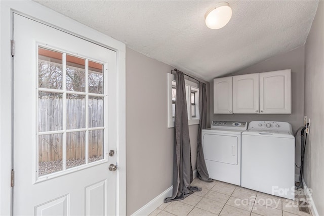 laundry area featuring light tile patterned floors, cabinet space, a textured ceiling, separate washer and dryer, and baseboards