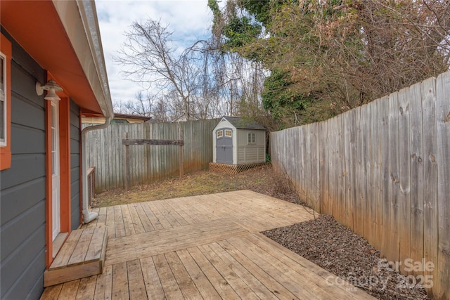 deck with a fenced backyard, a storage unit, and an outbuilding