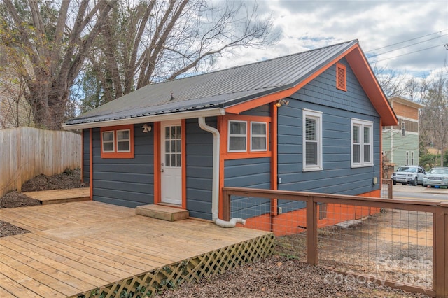 exterior space featuring a deck, metal roof, and fence