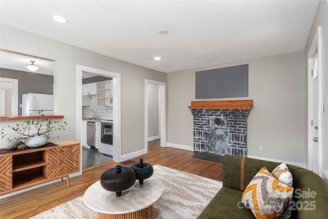 living area with a brick fireplace, baseboards, dark wood finished floors, and a textured ceiling