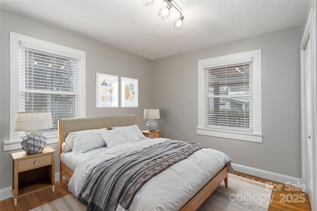 bedroom with multiple windows, baseboards, and wood finished floors