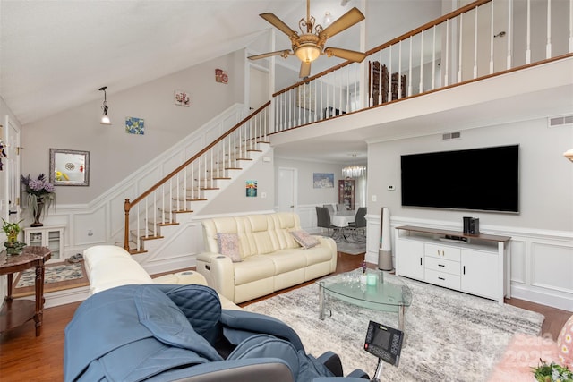 living room featuring hardwood / wood-style flooring, a towering ceiling, ornamental molding, and ceiling fan