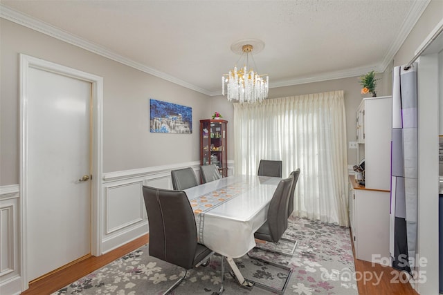 dining space featuring ornamental molding, light wood-type flooring, and a notable chandelier