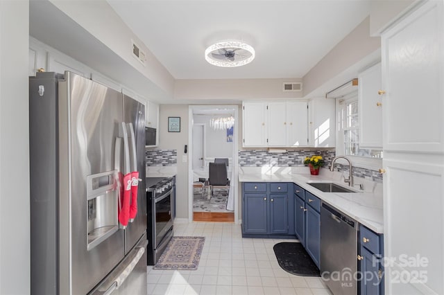 kitchen featuring appliances with stainless steel finishes, tasteful backsplash, sink, white cabinets, and blue cabinetry