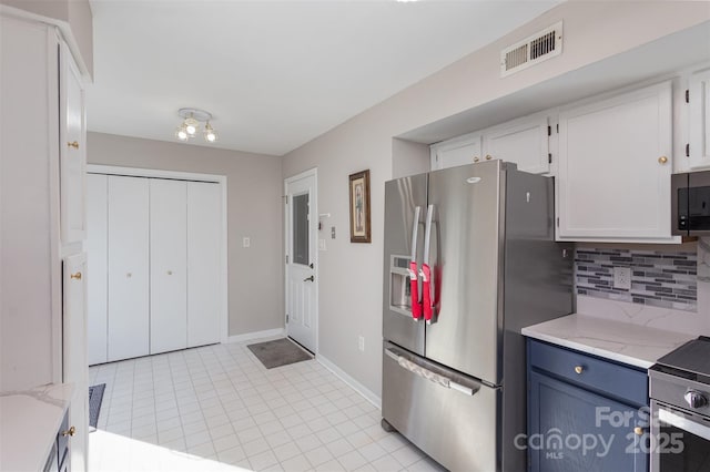 kitchen featuring appliances with stainless steel finishes, blue cabinets, white cabinetry, tasteful backsplash, and light tile patterned floors