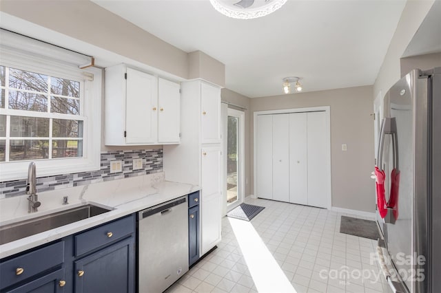 kitchen featuring blue cabinets, sink, white cabinetry, tasteful backsplash, and stainless steel appliances