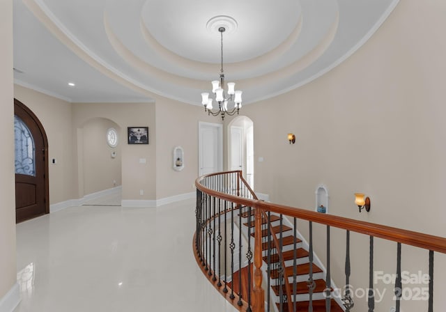 hallway with an inviting chandelier, a tray ceiling, and crown molding