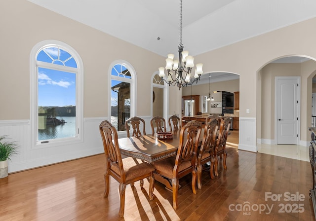 dining room featuring hardwood / wood-style flooring, a water view, and a chandelier