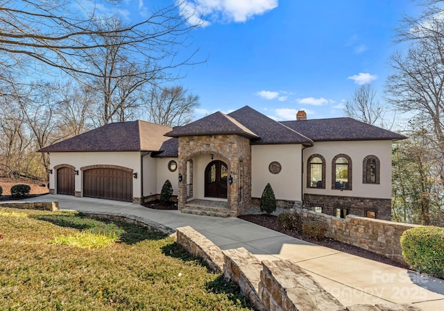 french country style house featuring driveway, stone siding, a chimney, stucco siding, and an attached garage