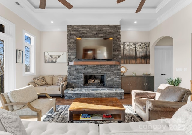 living area with visible vents, ceiling fan, ornamental molding, wood finished floors, and arched walkways