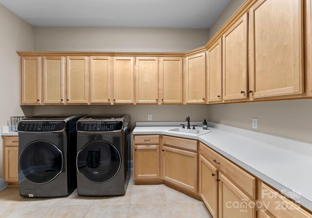 laundry area featuring washer and clothes dryer, cabinet space, a sink, and light tile patterned floors