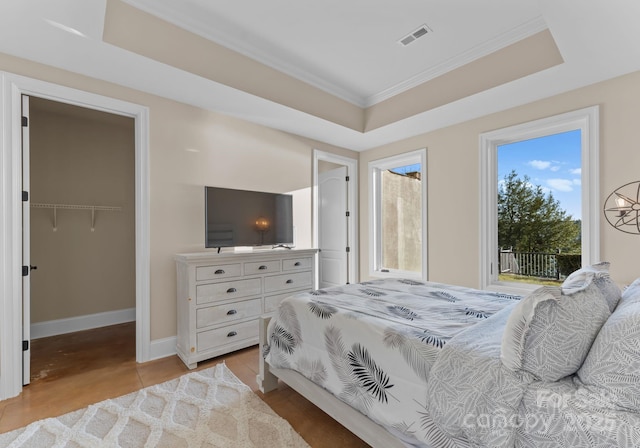 bedroom featuring visible vents, baseboards, access to outside, a tray ceiling, and a spacious closet