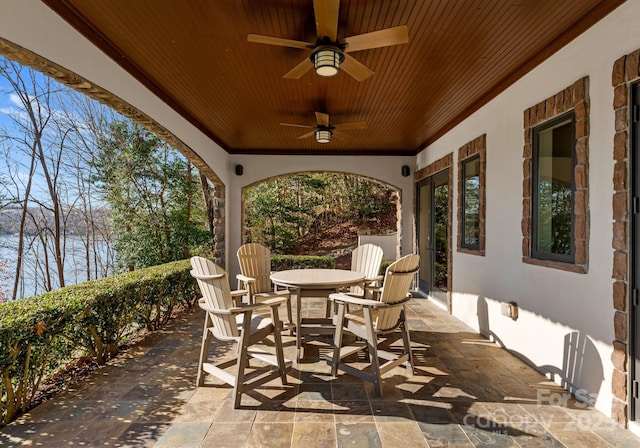 view of patio with outdoor dining space, a ceiling fan, and radiator