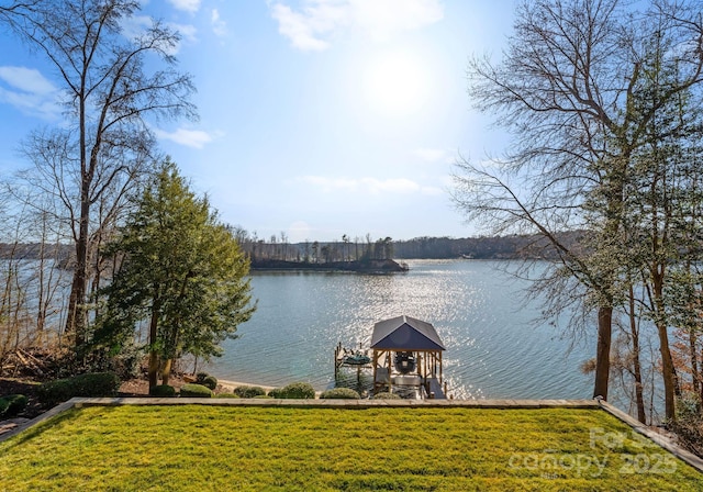 dock area featuring a water view, a lawn, and boat lift