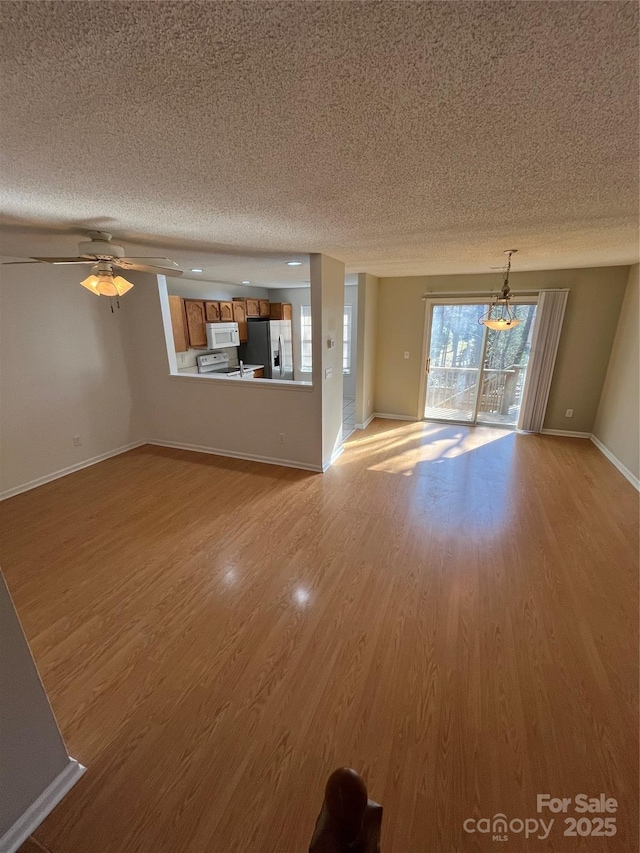 unfurnished living room with ceiling fan, a textured ceiling, and light wood-type flooring