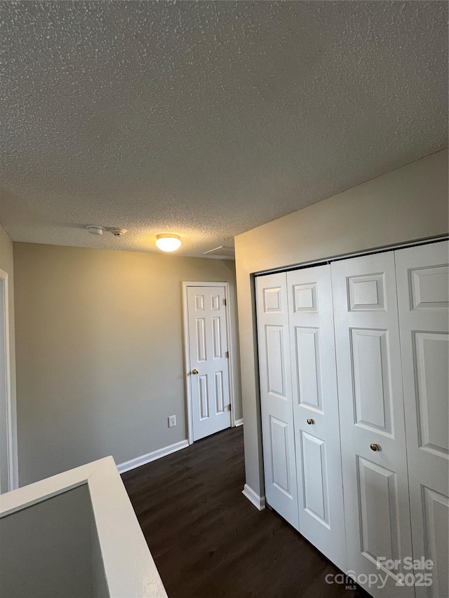 corridor with dark hardwood / wood-style floors and a textured ceiling