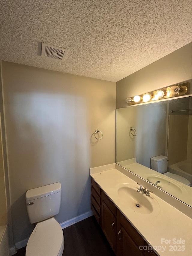 bathroom with vanity, wood-type flooring, toilet, and a textured ceiling