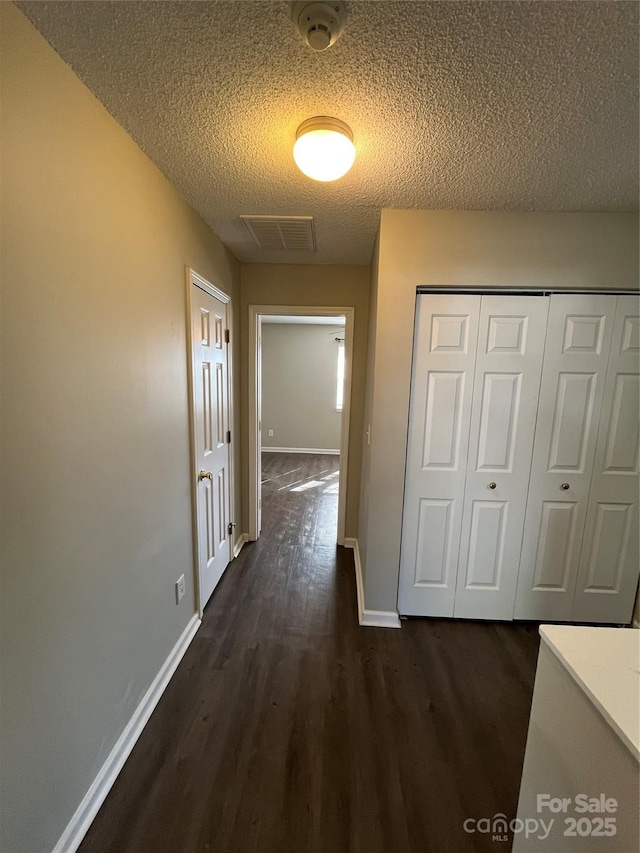 hall with dark hardwood / wood-style floors and a textured ceiling