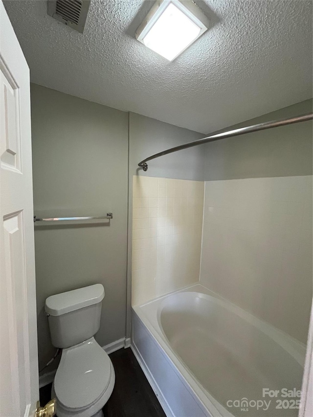 bathroom featuring tub / shower combination, a textured ceiling, and toilet