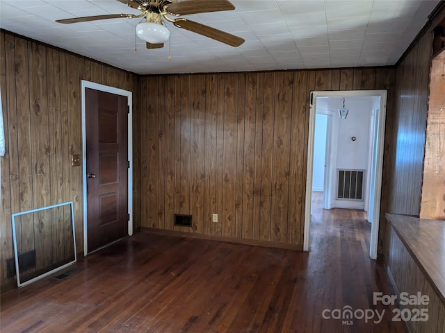 spare room featuring wooden walls, ceiling fan, and dark hardwood / wood-style flooring