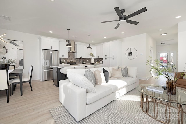 living room featuring ceiling fan, sink, and light wood-type flooring