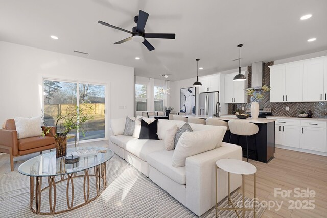 living room with sink, light hardwood / wood-style floors, and ceiling fan