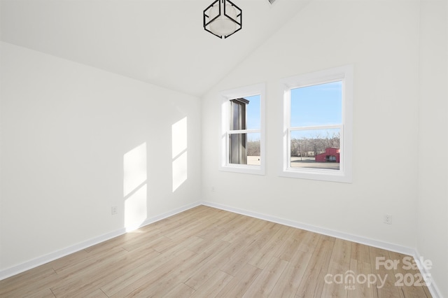 unfurnished room with vaulted ceiling and light wood-type flooring