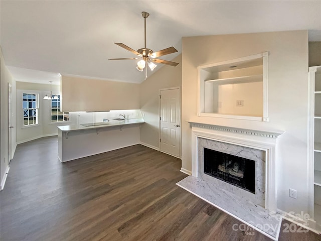 unfurnished living room with lofted ceiling, sink, ceiling fan, a fireplace, and dark hardwood / wood-style flooring