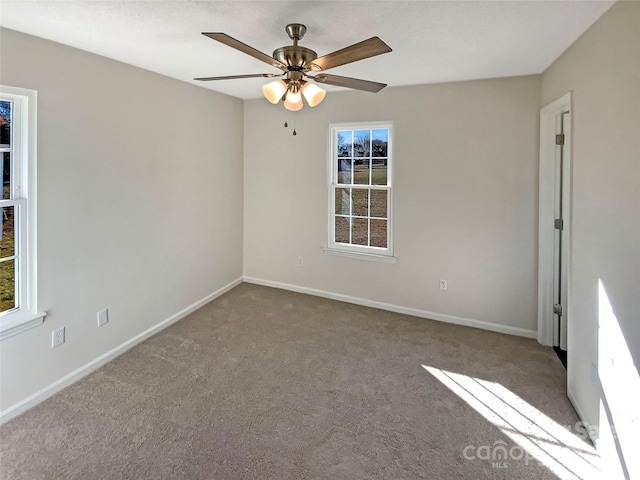 carpeted spare room with ceiling fan and plenty of natural light