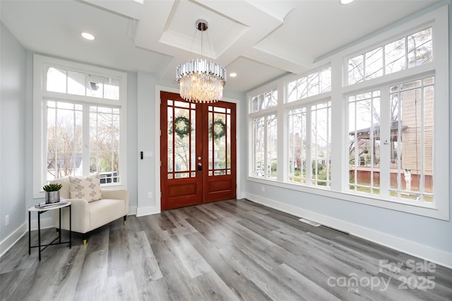 foyer entrance featuring an inviting chandelier, coffered ceiling, hardwood / wood-style floors, and french doors