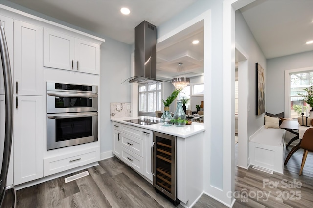 kitchen featuring white cabinetry, island range hood, beverage cooler, and stainless steel double oven